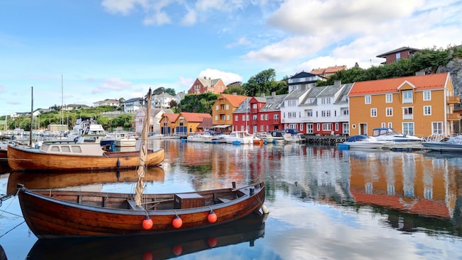 A mix of wooden and power boats docked in the harbor of Haugesund, Norway, alongside picturesque buildings A mix of wooden and power boats docked in the harbor of Haugesund, Norway, alongside picturesque buildings