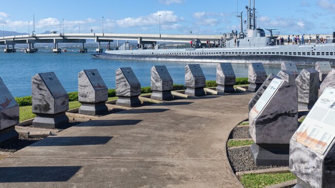 Una pasarela con esculturas de piedra con placas informativas con vistas al agua y al submarino Battleship Missouri