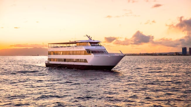 A multilevel ship sailing through open water at sunset A multilevel ship sailing through open water at sunset