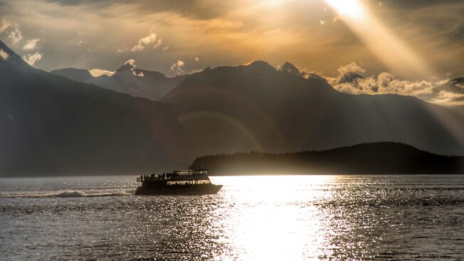A vessel in a body of water and the silhouettes of mountains in the distance