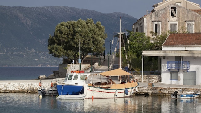 2 small wooden boats docked near 2 waterfront buildings 2 small wooden boats docked near 2 waterfront buildings