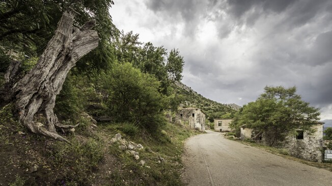 Un camino de tierra en una ladera de montaña con edificios rústicos
