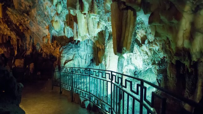 Stalactite formations inside a large cave with a walkway