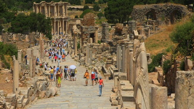 Crowds of people walk along a street in ancient Ephesus