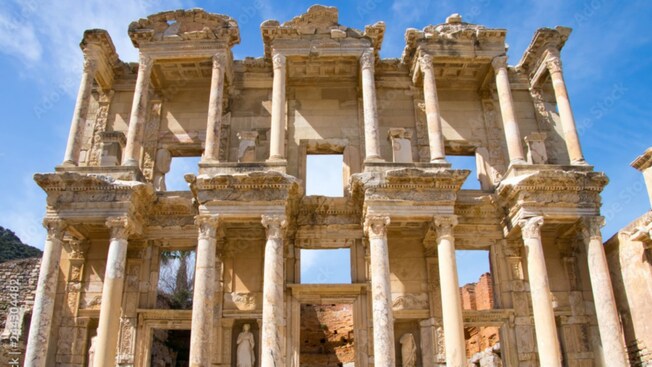 The ruins of an ancient 2 story building reveals columns and statues
