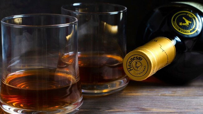 2 glasses containing whiskey next to a cognac bottle