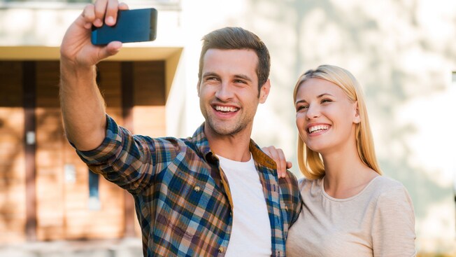 A man and a woman smile while taking a selfie