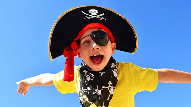 Um menino vestindo um chapéu pirata, um tapa-olho e uma bandana de caveiras
