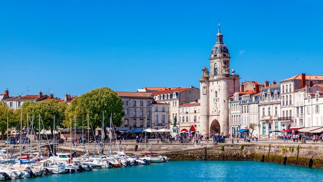 The old port in La Rochelle, France reveals a medieval retaining wall and an imposing clock tower