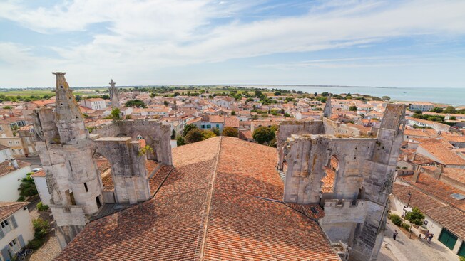 Un techo de cerámica de terracota con ruinas de piedra con vistas a un pueblo costero