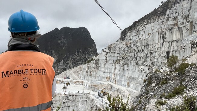 A tour guide wearing a safety vest looking out at a marble quarry