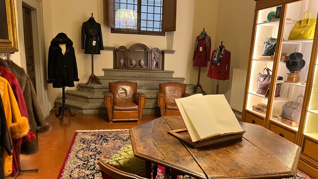 A showroom displaying leather purses, hats, books and coats