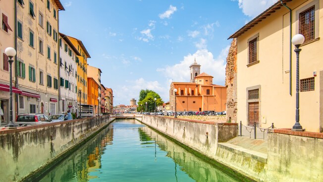 A canal between buildings with a church and a clock tower in the distance