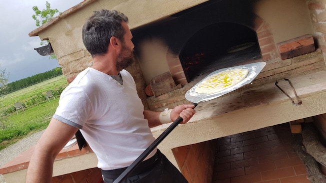 Man putting pizza into a masonry oven Man putting pizza into a masonry oven