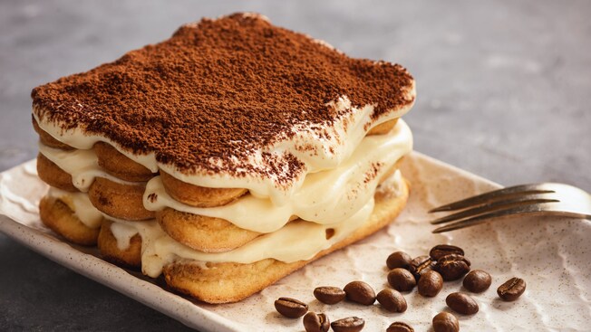Tiramisú en un plato con un tenedor y granos de café