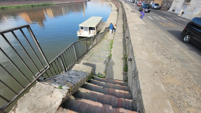 Stairs leading to a catamaran docked in the Arno River in the Tuscany region of Italy