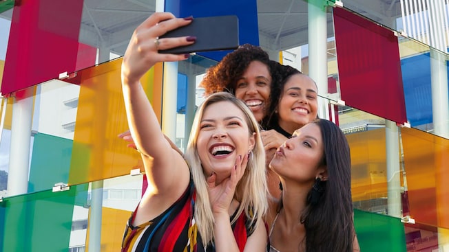 4 girls take a selfie in front of a structure of glass panels 4 girls take a selfie in front of a structure of glass panels