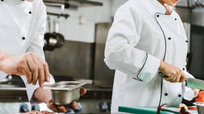 Dois chefs preparando uma refeição na cozinha de um restaurante
