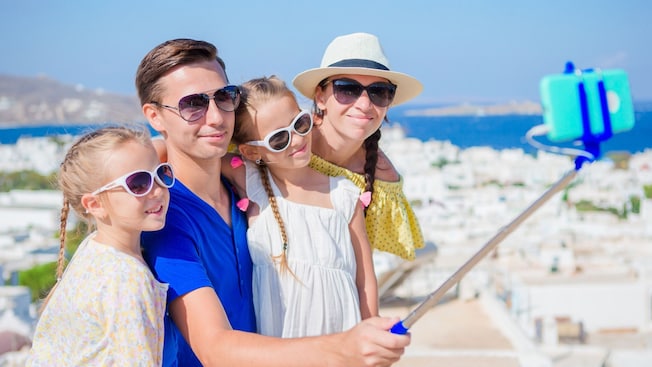 A family posing as the dad holds a camera on a selfie stick A family posing as the dad holds a camera on a selfie stick