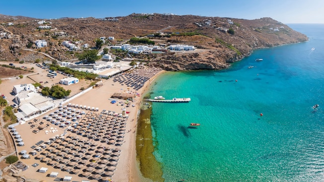 A beach lined with rows of lounge chairs A beach lined with rows of lounge chairs
