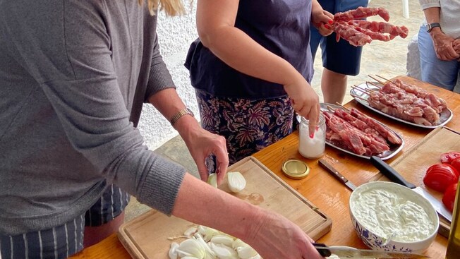 Un grupo de personas cocinando comida griega en Miconos, Grecia
