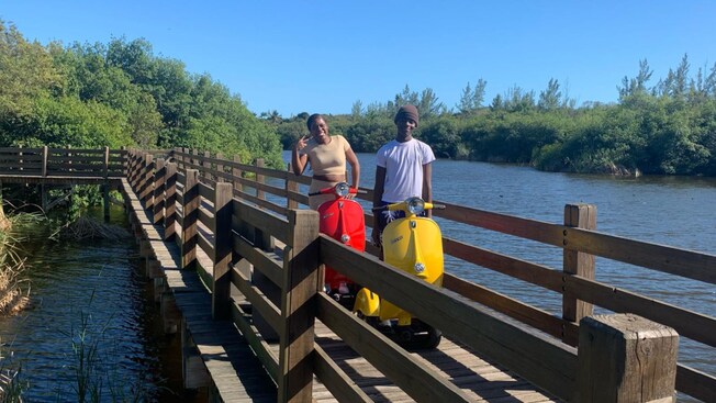 Two Guests on scooters crossing a bridge over a lake