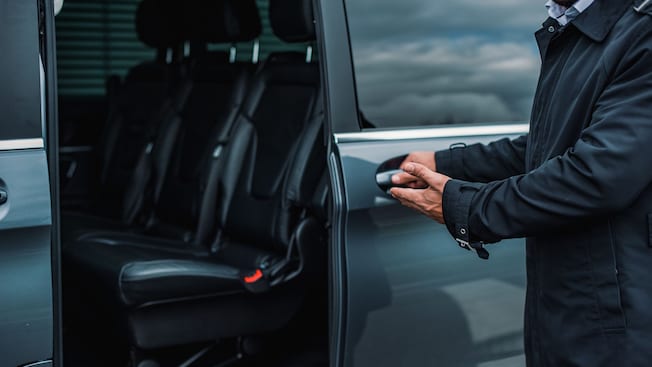 A private driver opening the door of a luxury van A private driver opening the door of a luxury van