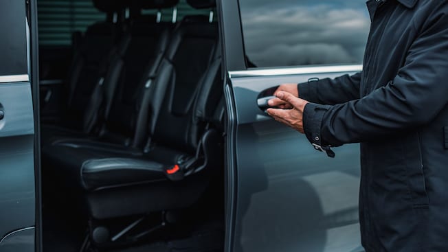 A private driver opening the door of a luxury van A private driver opening the door of a luxury van