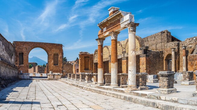 The ruins of Pompeii reveal a stone road lined with columns, arches and former buildings