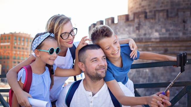 Una familia sonriente posa para una foto con un brazo extensible para tomar selfis Una familia sonriente posa para una foto con un brazo extensible para tomar selfis
