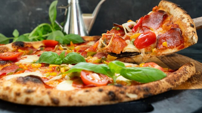 Neapolitan pizza topped with cherry tomatoes, pepperoni, peppers, cheese and basil