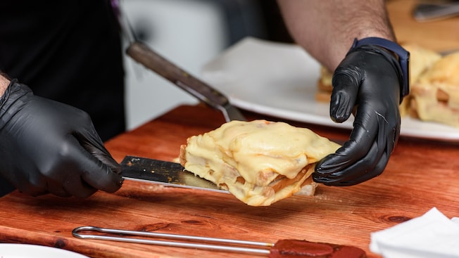 A chef preparing a serving of Francesinha, a Portuguese sandwich covered in melted cheese A chef preparing a serving of Francesinha, a Portuguese sandwich covered in melted cheese
