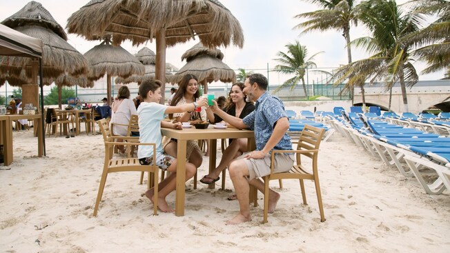 A family of 4 sitting at a table, clinking their glasses together