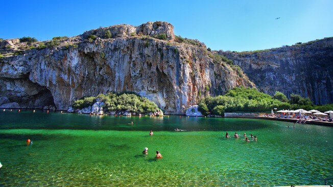 Personas nadando cerca de un acantilado en el lago Vouliagmeni en Atenas, Grecia.