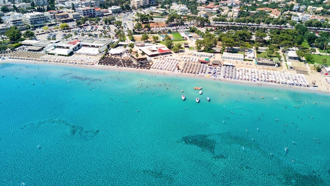 A shoreline along the Athenian Riviera featuring a spacious beach against a cityscape A shoreline along the Athenian Riviera featuring a spacious beach against a cityscape