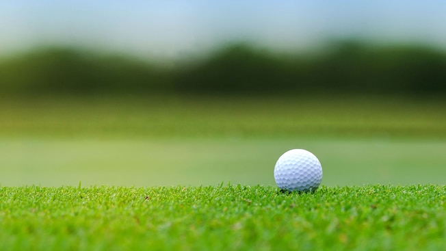 Una pelota de golf en un campo de golf con césped Una pelota de golf en un campo de golf con césped