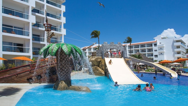 A área da piscina de um resort com uma área de recreação com tema tropical para crianças com toboáguas e fontes A área da piscina de um resort com uma área de recreação com tema tropical para crianças com toboáguas e fontes