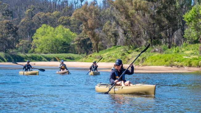A small group of kayakers paddling on the Pambula River in New South Wales, Australia