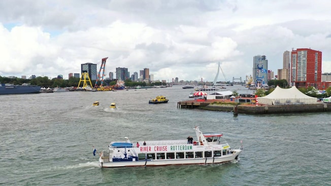A boat along the Port of Rotterdam with ‘River Cruise Rotterdam’ written on the vessel’s surface A boat along the Port of Rotterdam with ‘River Cruise Rotterdam’ written on the vessel’s surface