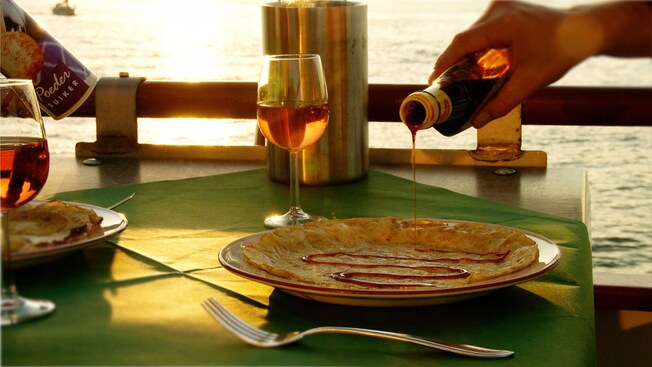 A hand pouring syrup on to a pancake