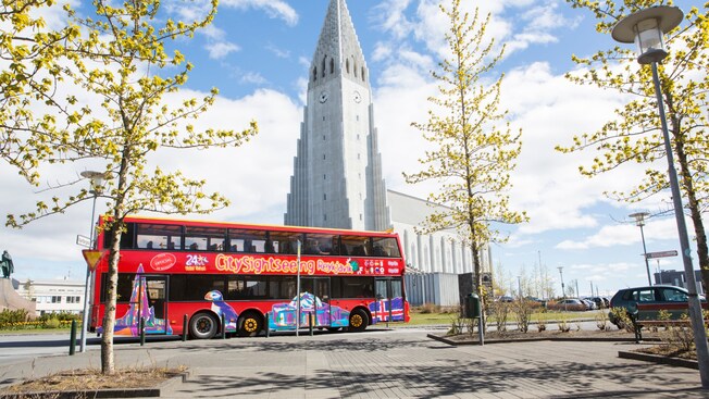 A double decker bus parked between a church and a park