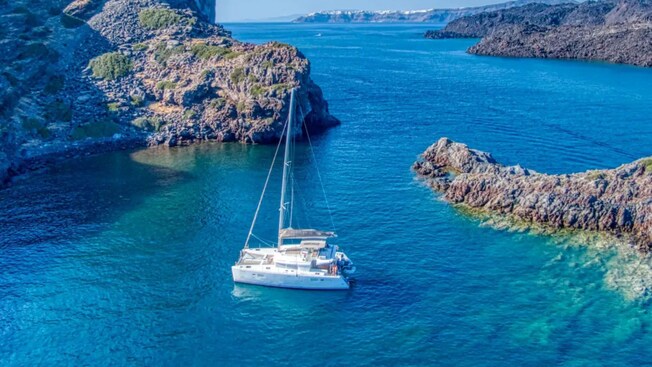 Un catamarán flotando en el mar Mediterráneo cerca de Santorini, Grecia