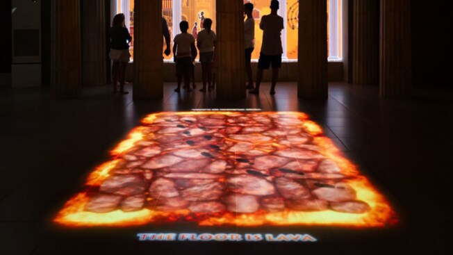 Silhouettes of people viewing a lava exhibit
