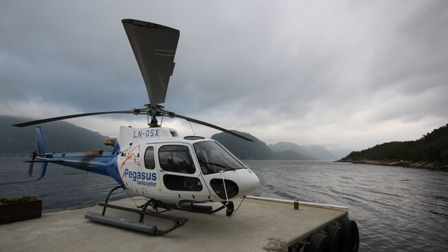 A helicopter with the words ‘Pegasus helicopter’ waiting to take off on a helipad overlooking the water
