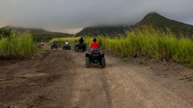 A group of people riding on ATVs along a dusty road in Basseterre, Saint Kitts and Nevis