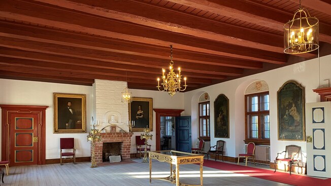 Una habitación grande decorada con muebles antiguos, pinturas y candelabros