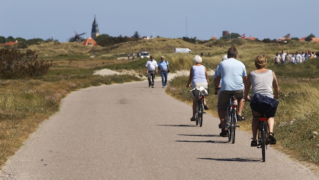 Personas paseando en bicicleta por un camino en el campo mientras otros caminan en la dirección opuesta Personas paseando en bicicleta por un camino en el campo mientras otros caminan en la dirección opuesta