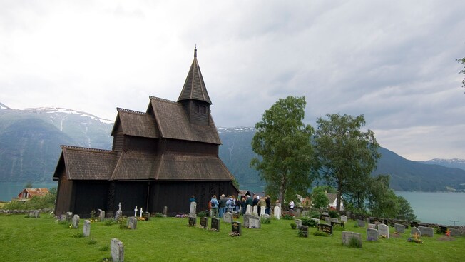 Hóspedes reunidos em torno da Igreja de madeira Urnes Stave, na Noruega