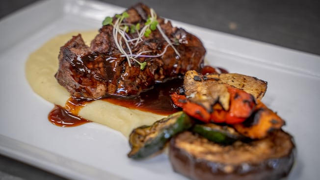 Steak served with a sauce and grilled vegetables. Steak served with a sauce and grilled vegetables.