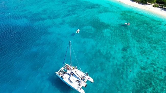 An aerial view of a catamaran anchored near a beach An aerial view of a catamaran anchored near a beach